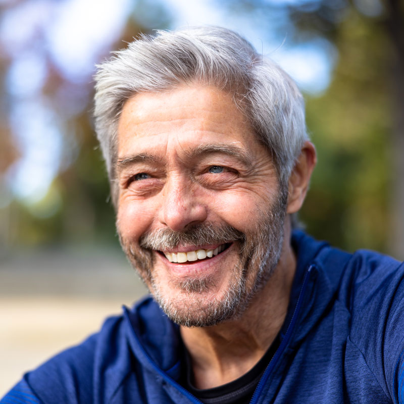 mature man with gray hair smiling outdoors