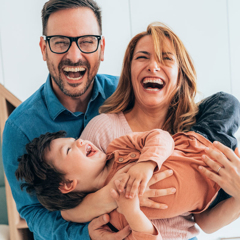 young family laughing while holding toddler son